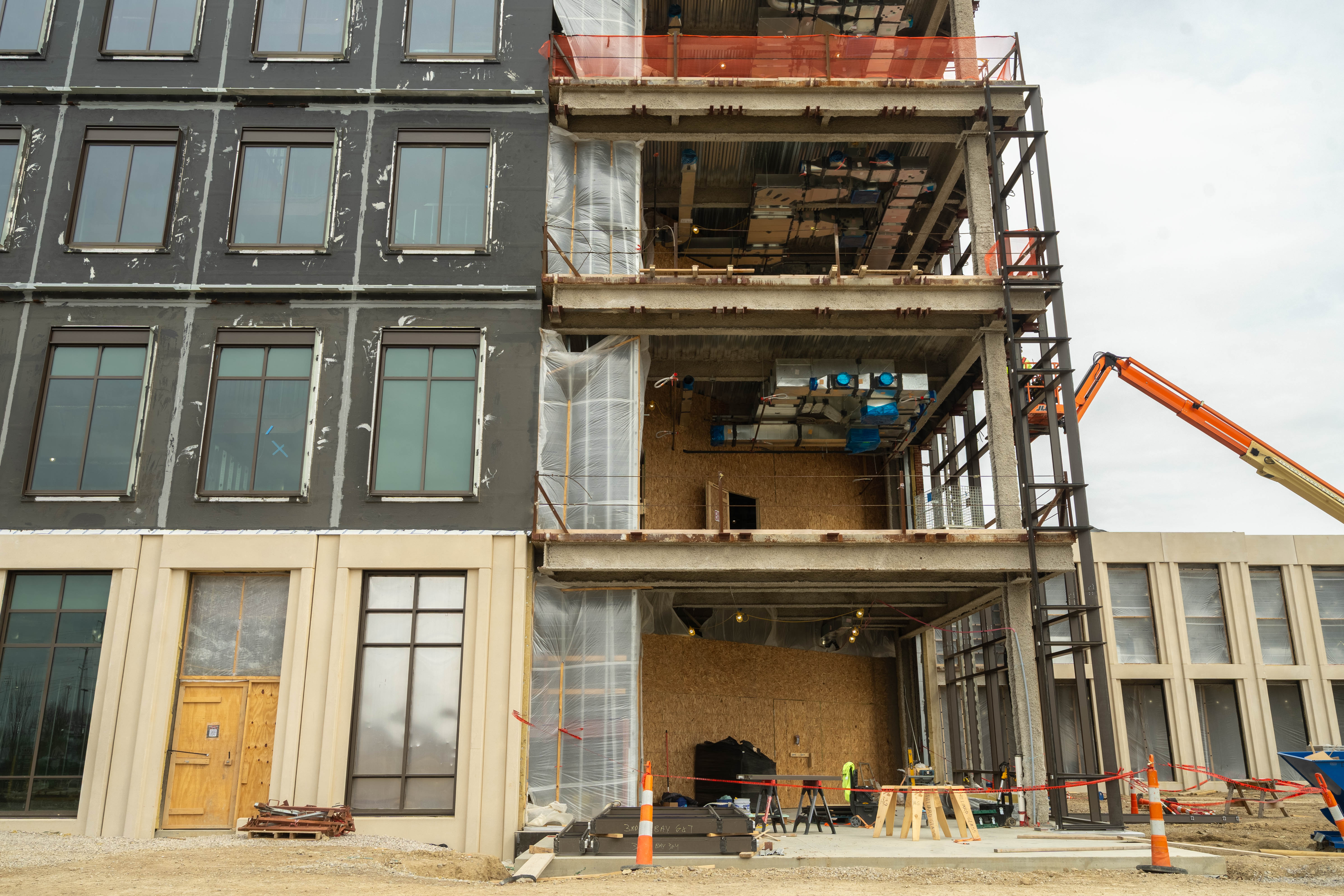 An exterior view of the building where crews are seen installing the curtain wall.