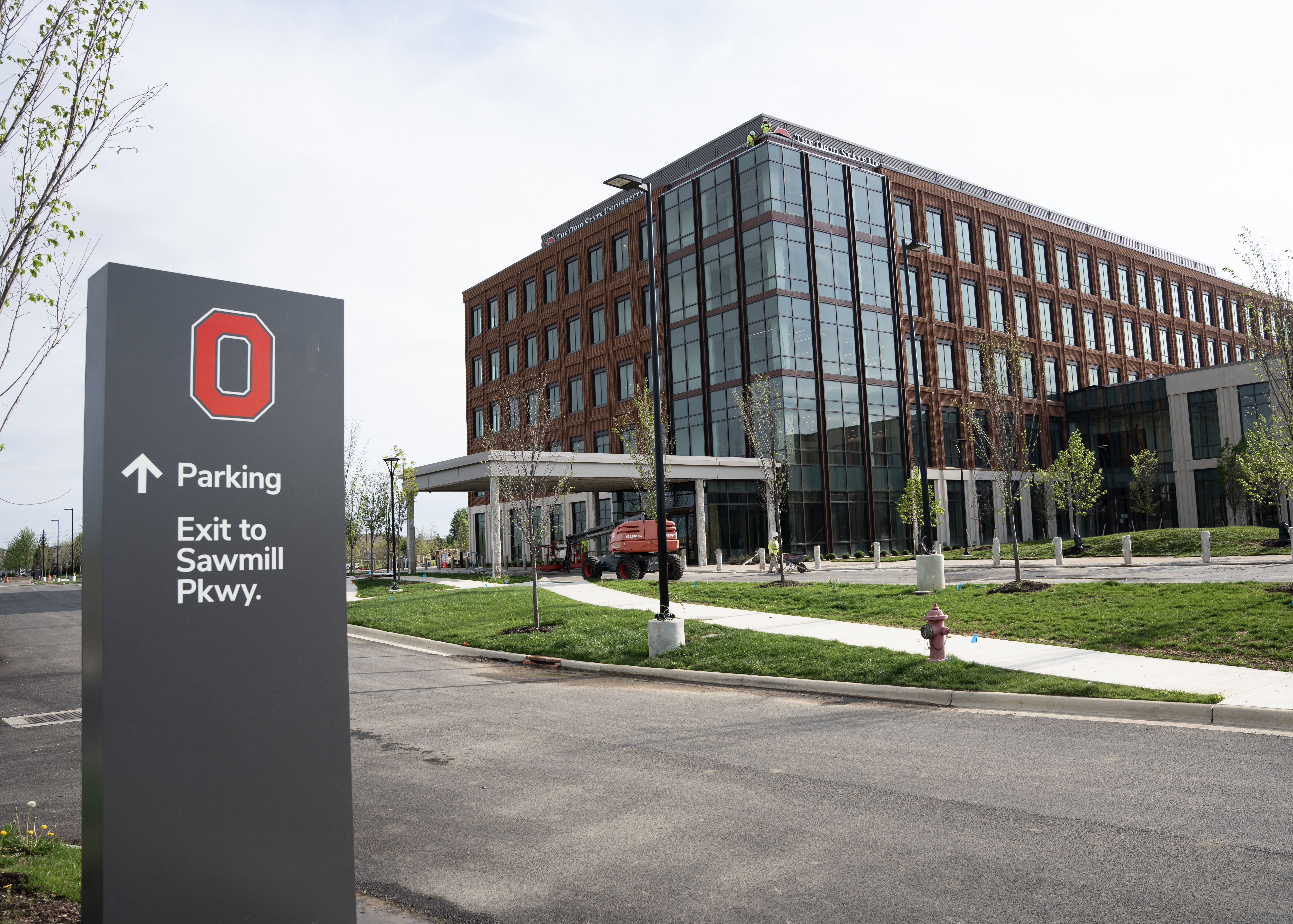 An exterior view of the building where a way finding sign is seen in the forefront.