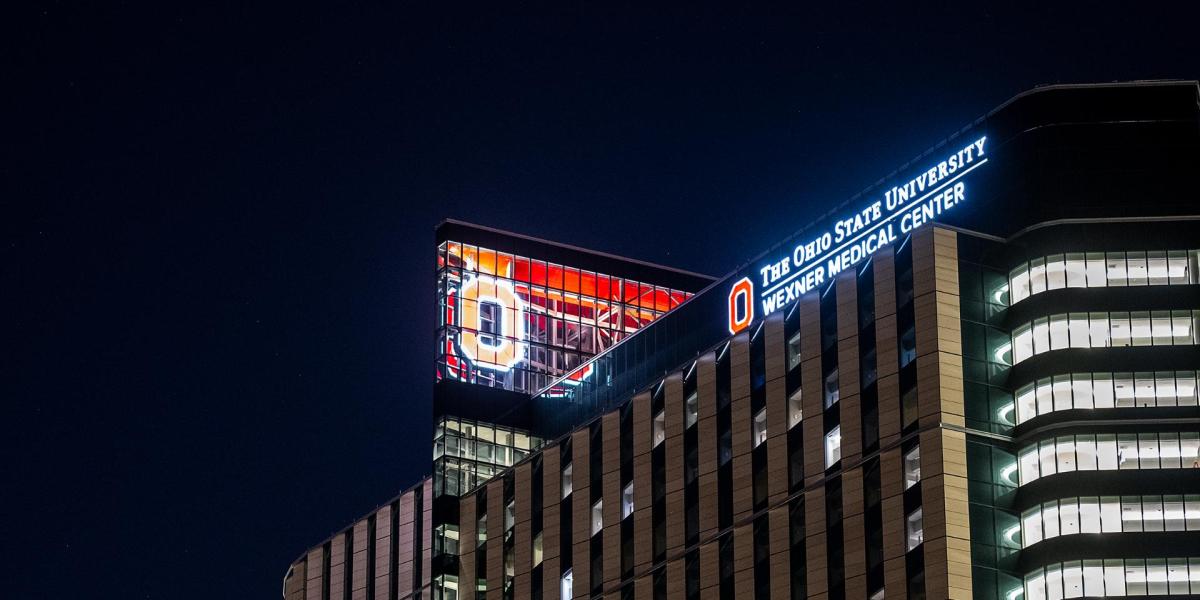A large Block O is illuminated scarlet at the top of the inpatient hospital.