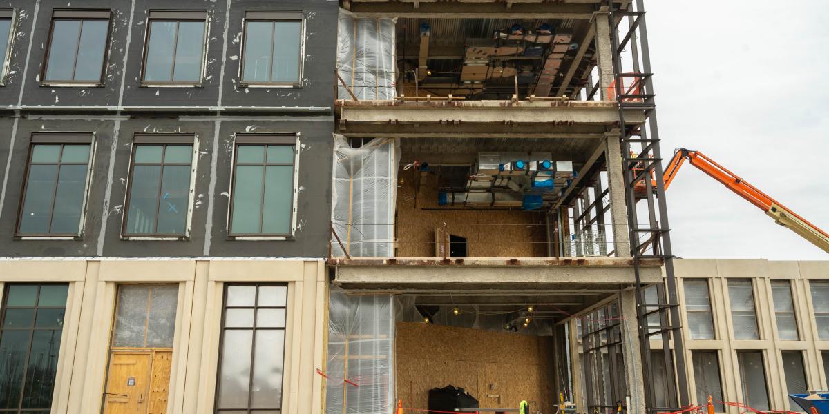 An exterior view of the building where crews are seen installing the curtain wall.