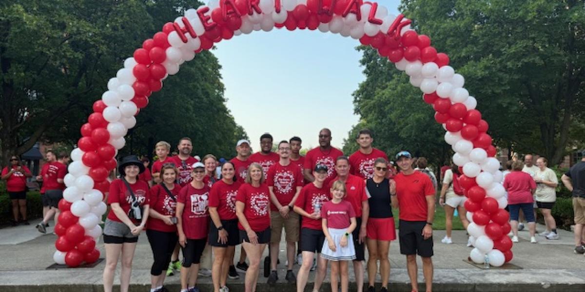 A group of people standing under a white and red balloon arch.
