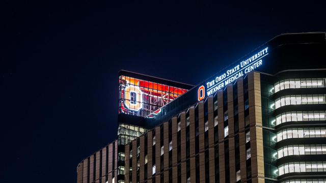 A large Block O is illuminated scarlet at the top of the inpatient hospital.
