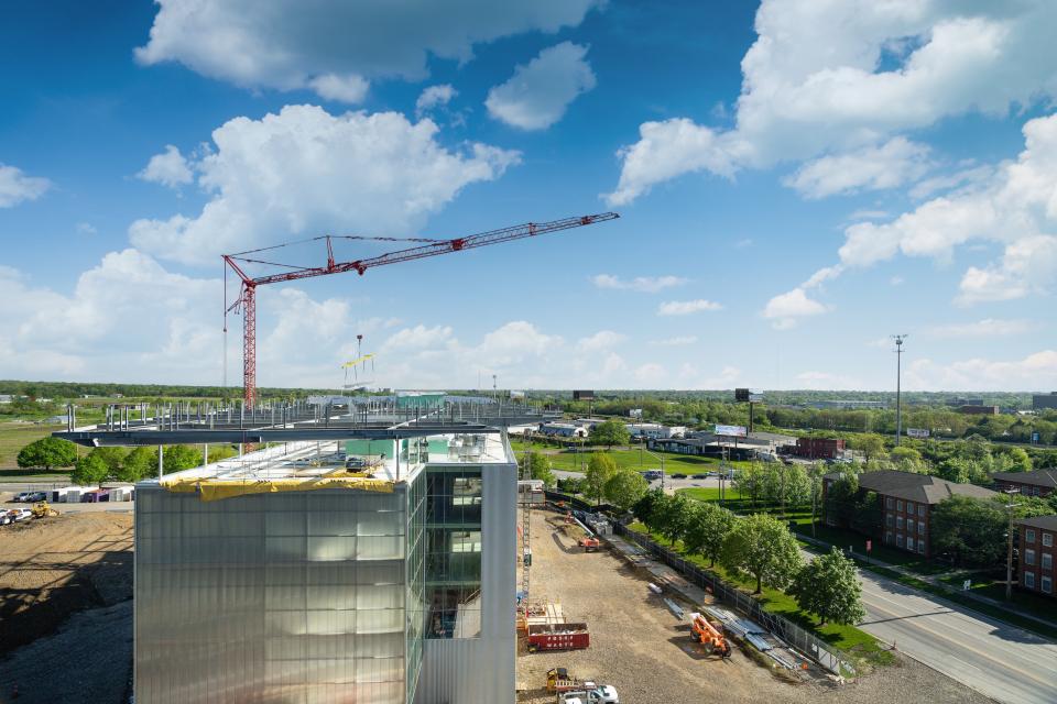A wide view of the crane and building as a crane carries a solar panel.