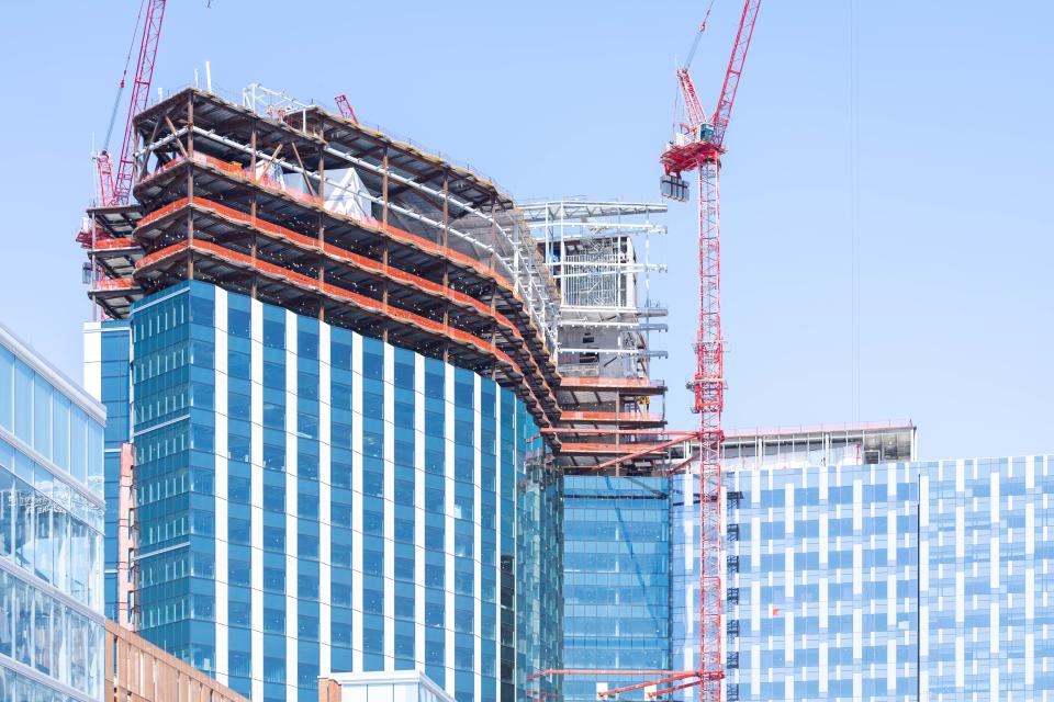 A view of the outside of the building where crews can be seen working on the exterior on a crane.