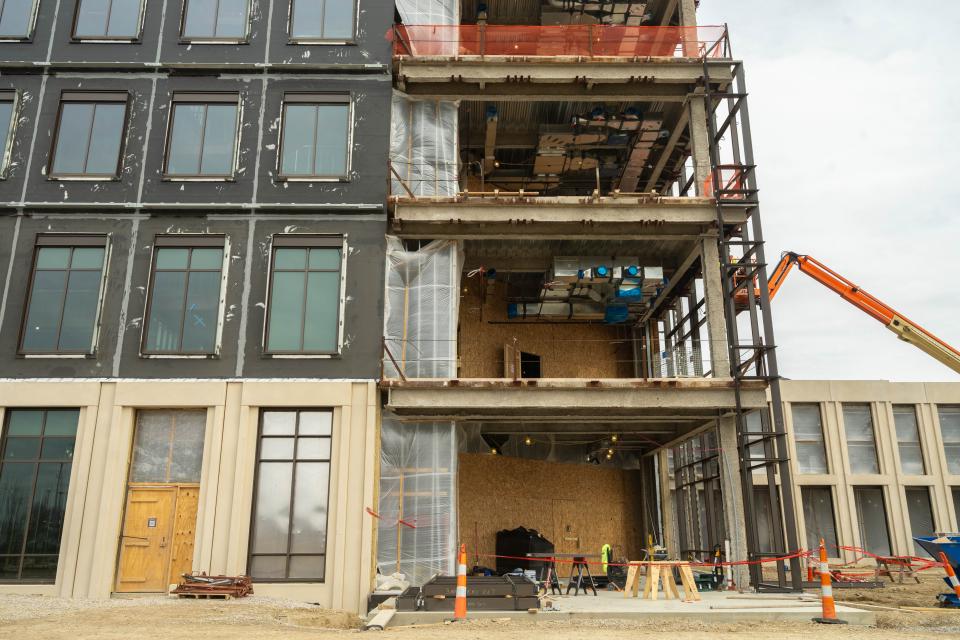 An exterior view of the building where crews are seen installing the curtain wall.