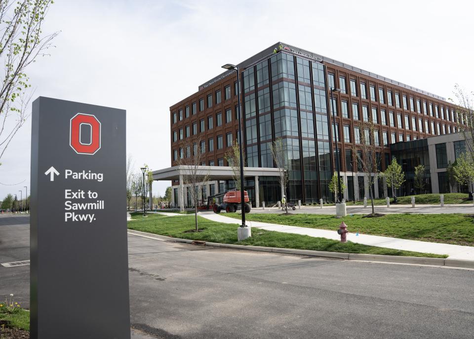 An exterior view of the building where a way finding sign is seen in the forefront.