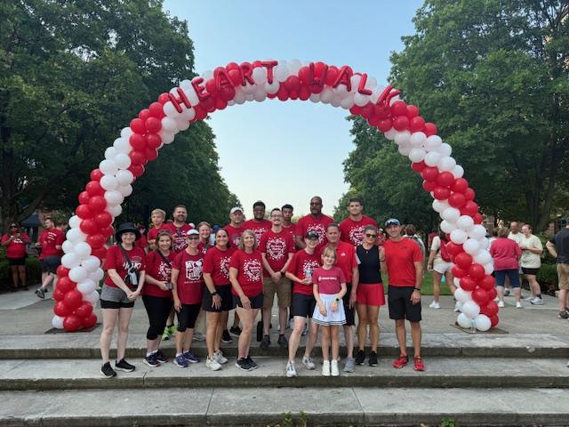 A group of people standing under a white and red balloon arch.